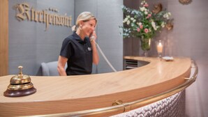 A reception desk with a wooden finish, a brass bell, and a wall-mounted sign. - Hotel Gasthof zum Kirchenwirt (Puch bei Hallein)