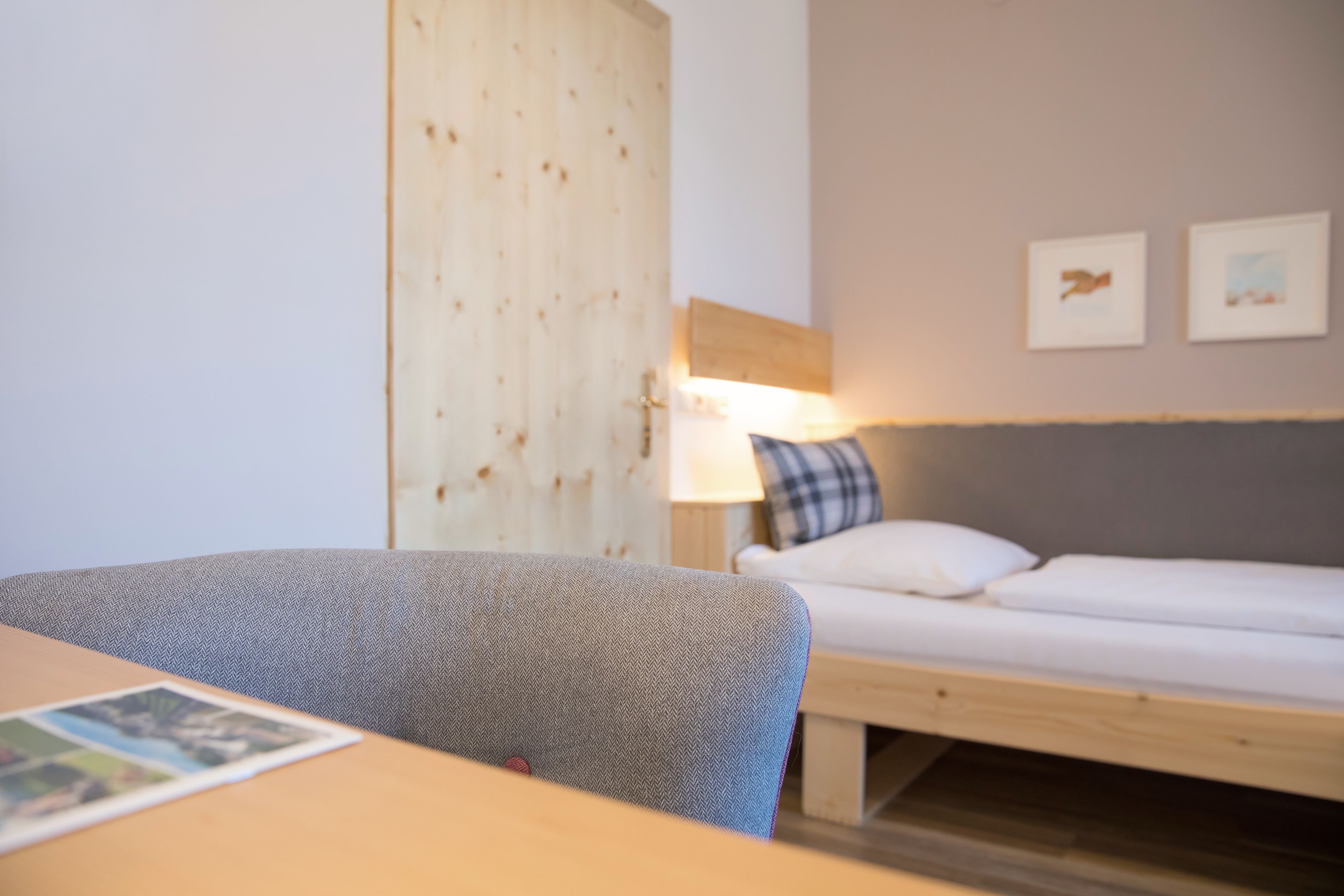 Una habitación con cama, escritorio y silla. Hay dos cuadros en la pared.