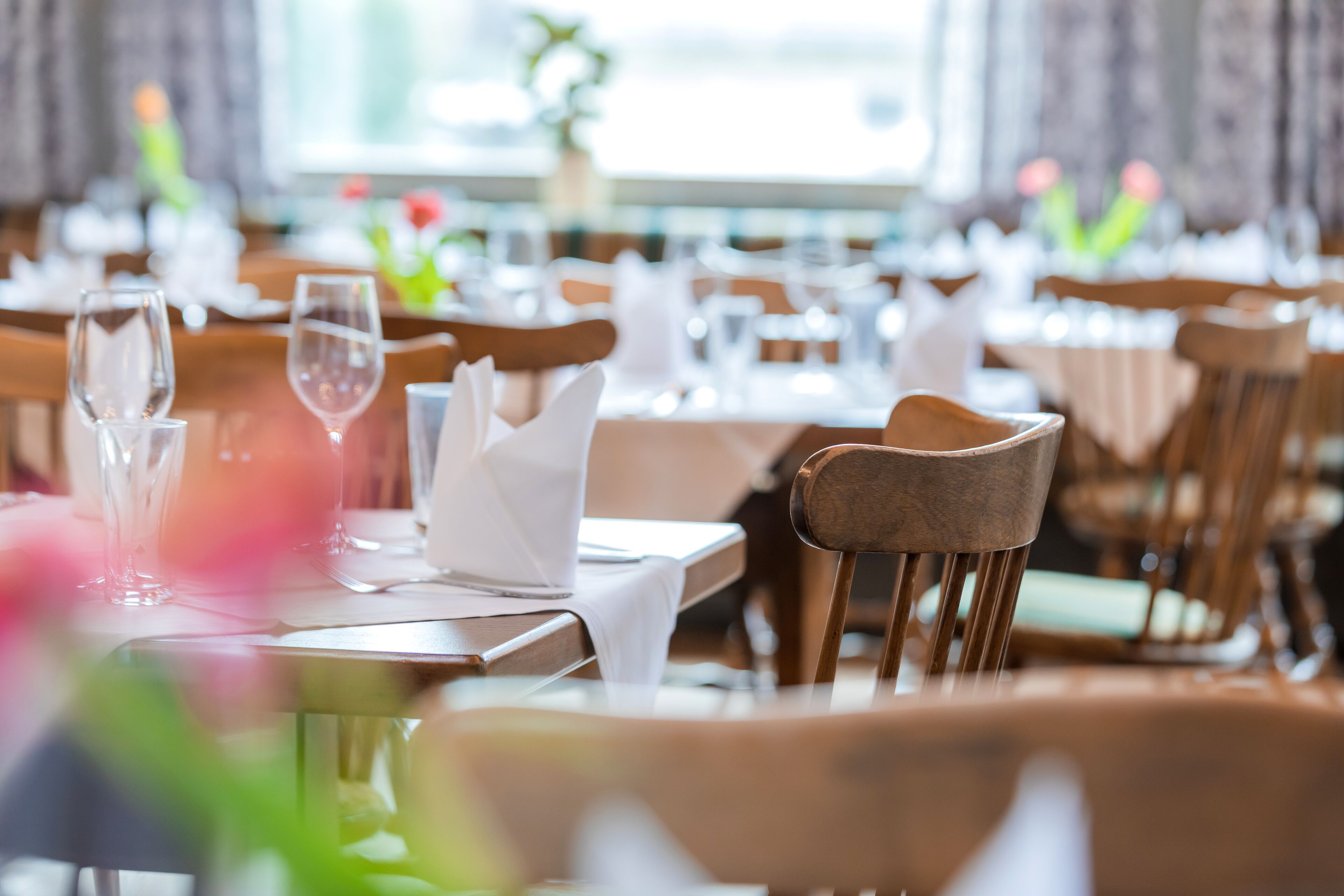 Ein Restaurantinneres mit ordentlich aufgestellten Tischen, Stühlen und klarem Glasgeschirr.
