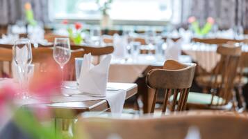 Ein Restaurantinneres mit ordentlich aufgestellten Tischen, Stühlen und klarem Glasgeschirr.
