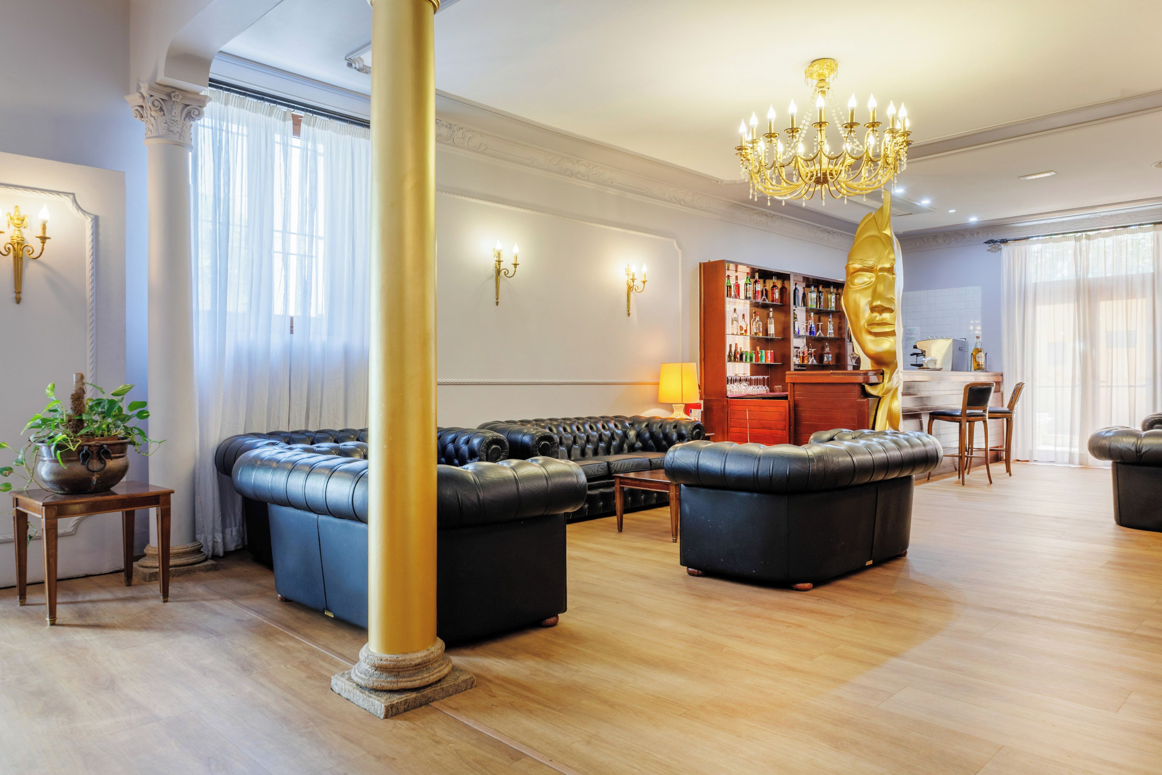 Ein geräumiges Wohnzimmer mit einem großen schwarzen Ledersofa, einem Holztisch und einer Chandelier.