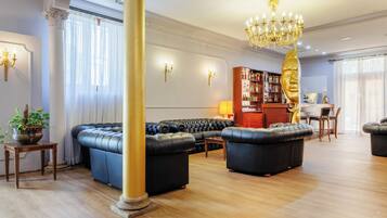 A spacious living room with a large black leather sofa, a wooden coffee table, and a chandelier.