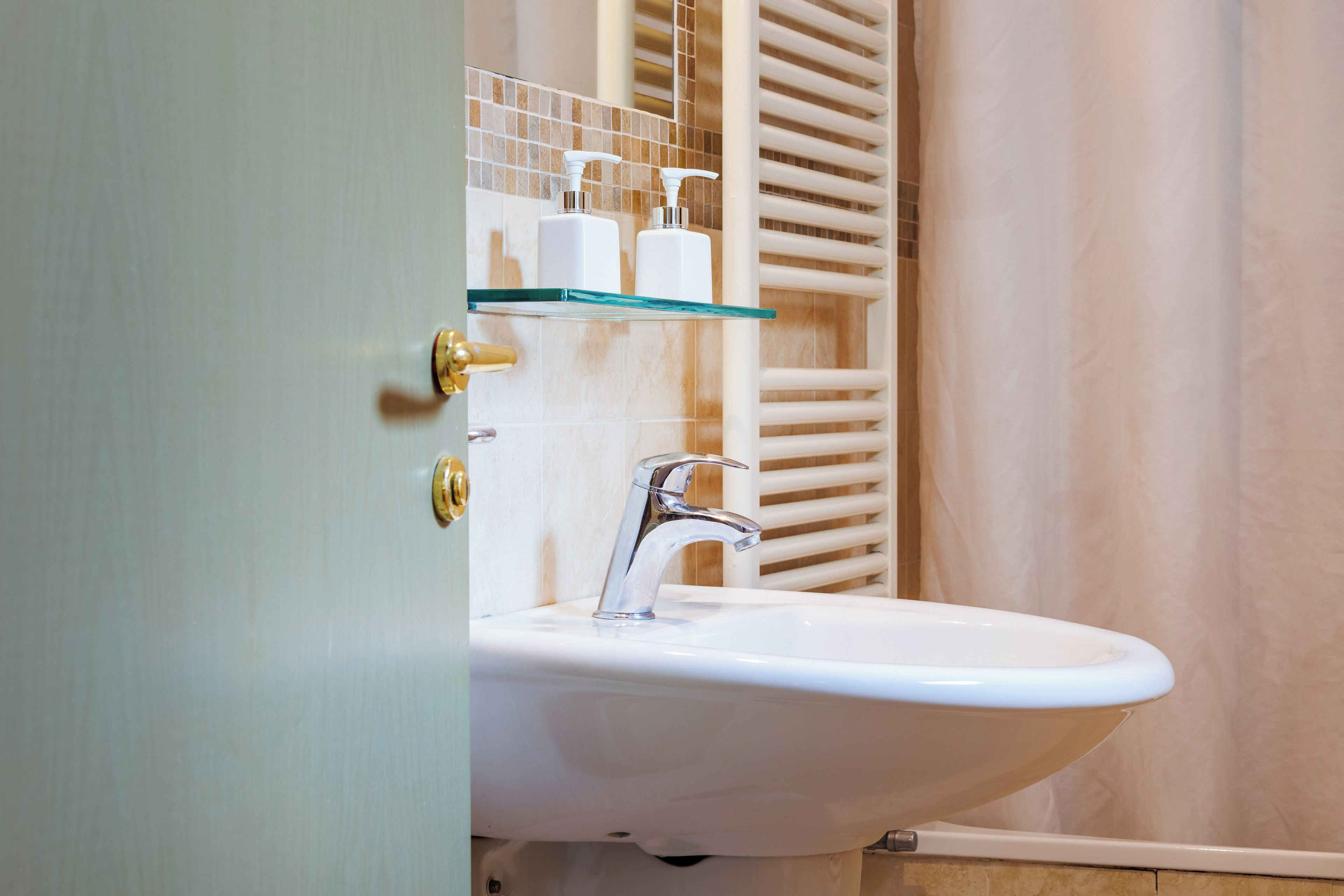 A bathroom with a white sink, a glass shelf, and a towel rack.