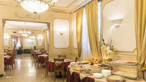 A banquet hall with tables set for dining, a buffet with various food items, and a chandelier. - Hotel Villa Rosa (Rome)