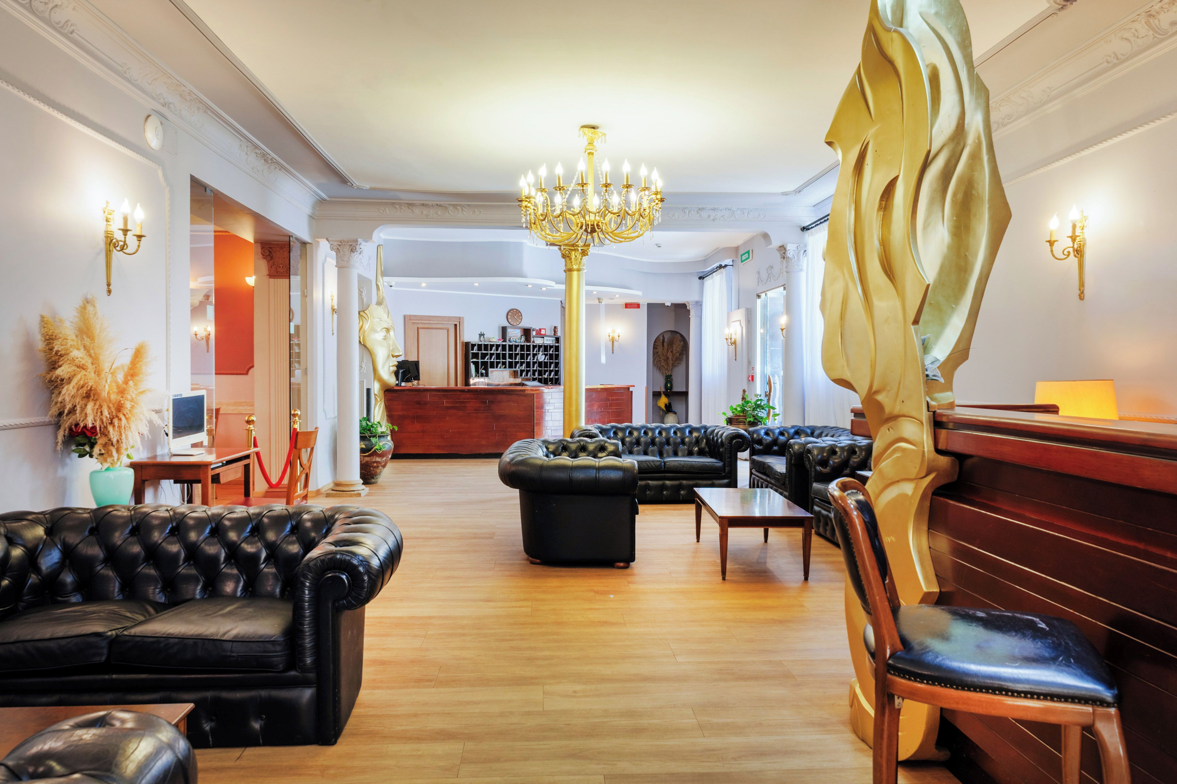 A lobby with leather sofas, a chandelier, and a reception desk.