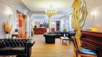 Un hall con sofás de cuero, un candelabro y un mostrador de recepción.