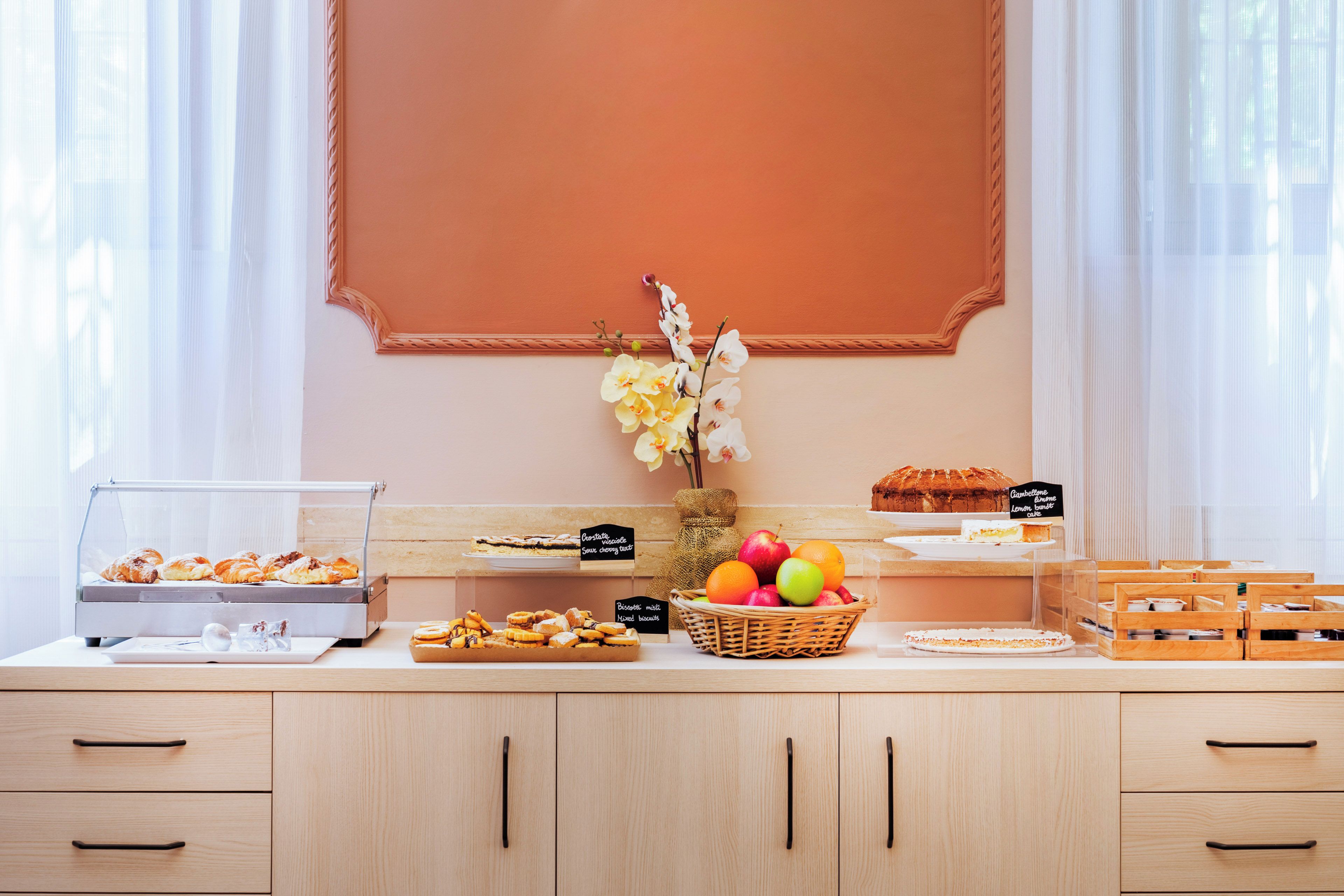 A breakfast buffet with pastries, fruits, and a cake display.