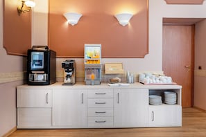 A hotel room with a kitchenette including a coffee maker, juice dispenser, and a bowl of fruit. - Hotel Villa Rosa (Rome)