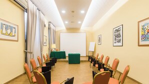 A conference room with rows of chairs, a projector screen, and artwork on the walls. - Hotel Villa Rosa (Rome)