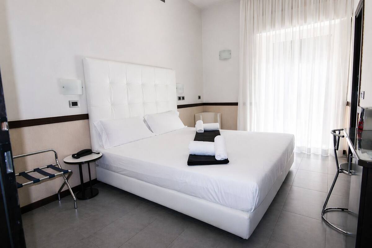 A hotel room with a large bed, bedside tables, a chair, and a desk.