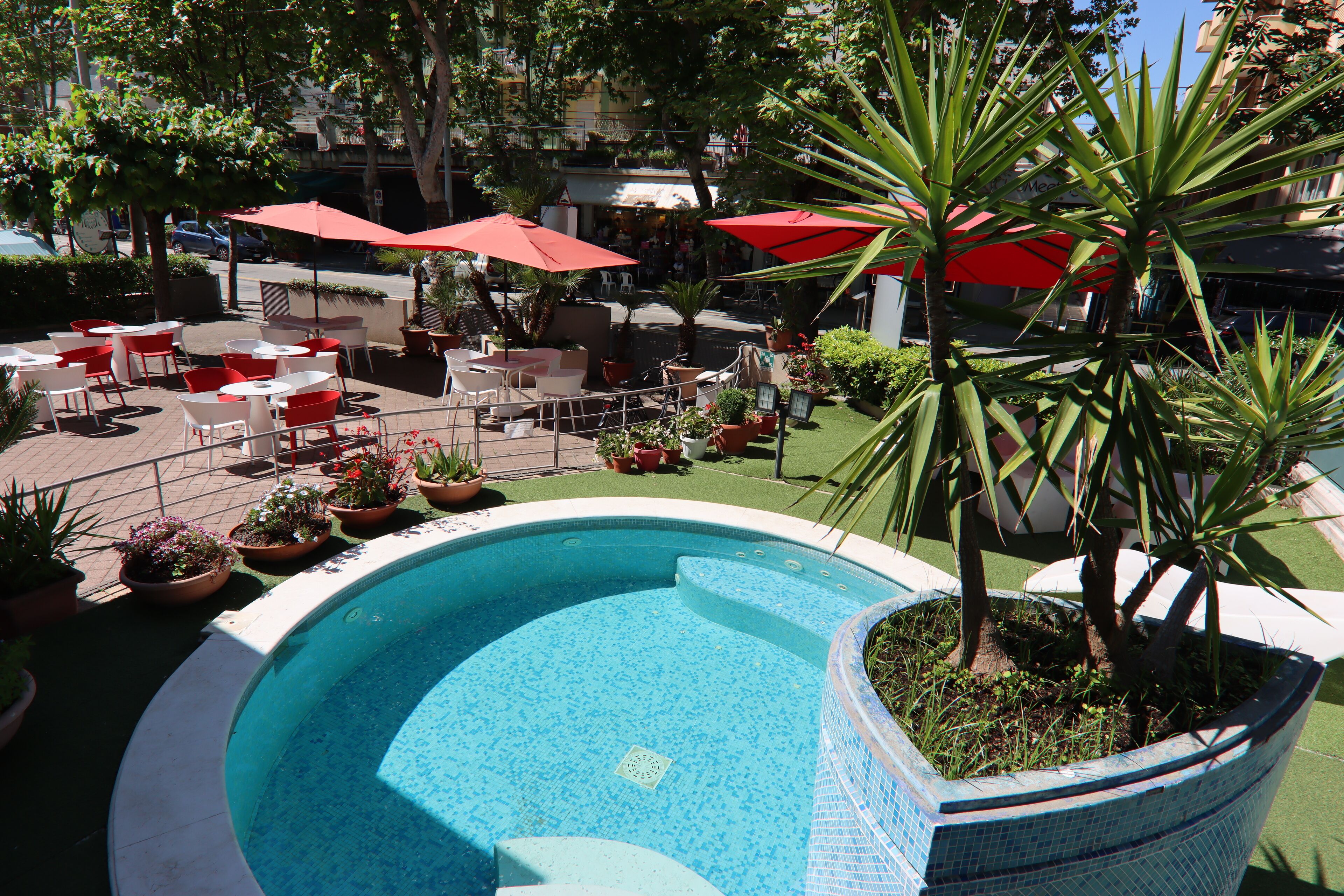 A swimming pool with surrounding patio furniture and potted plants.