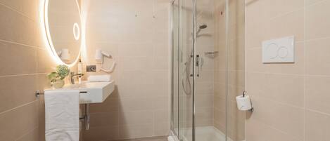 A modern bathroom with a glass-enclosed shower, a white sink with a mirror, and a toilet.