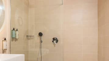 Een moderne badkamer met een douchecabine van glas, een houten wastafelmeubel en beigetegels.
