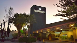 Hotel amb una torre destacada amb el text “REAEMINAS”, façana de pedra, zona d'estar a l'exterior i pati paisatjista.