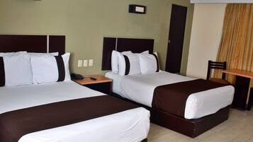 A hotel room with two beds, a nightstand, a chair, and a small table.
