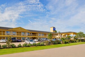 Un motel de varios pisos con estacionamiento, un área de estar al aire libre techada y un letrero que indica una calificación de 3 estrellas.