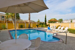 Una piscina con sillones de descanso y una sombrilla.