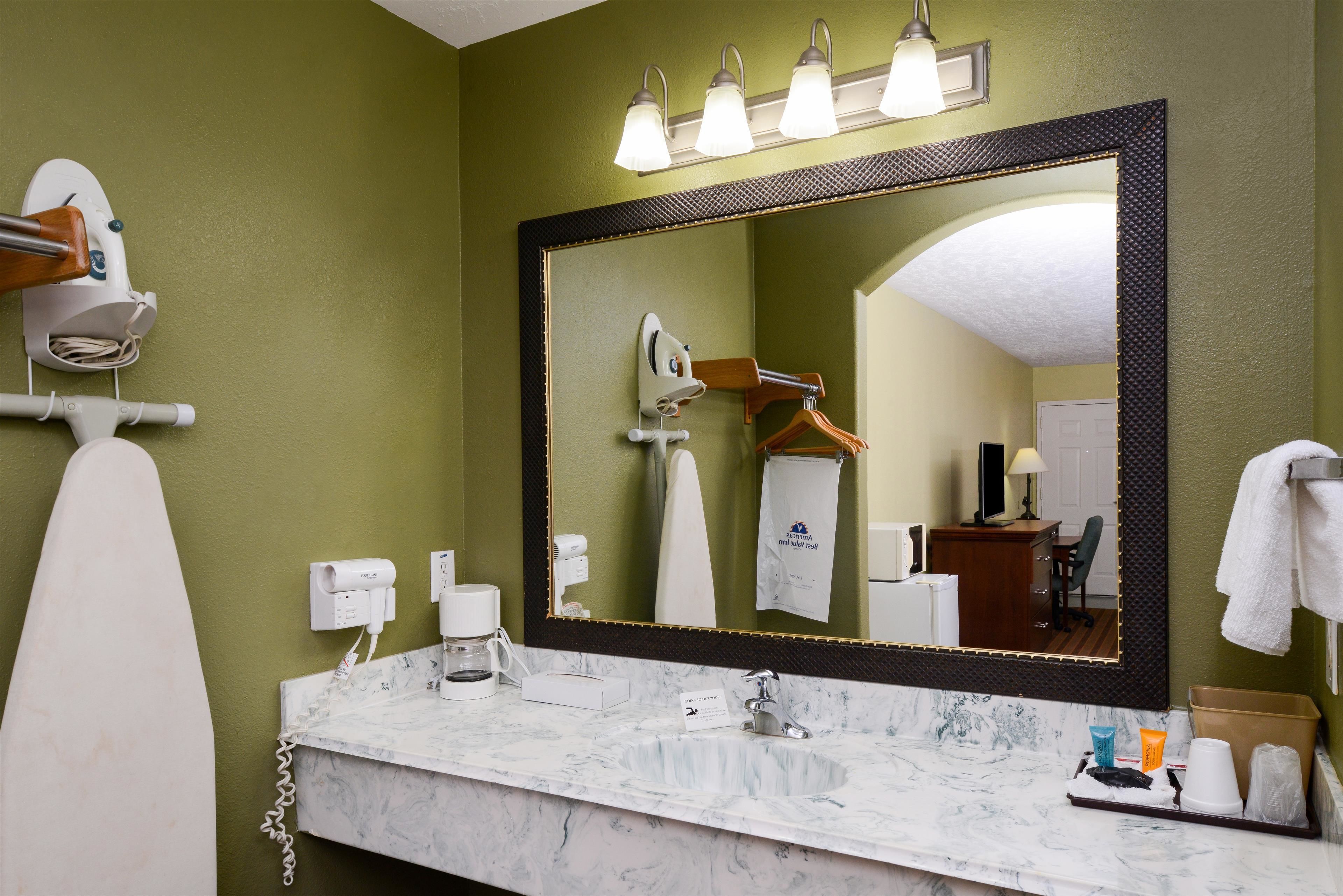 A bathroom with a large mirror, a white sink, and a towel rack.