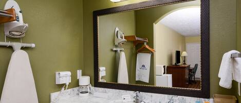 A bathroom with a large mirror, a white sink, and a towel rack.