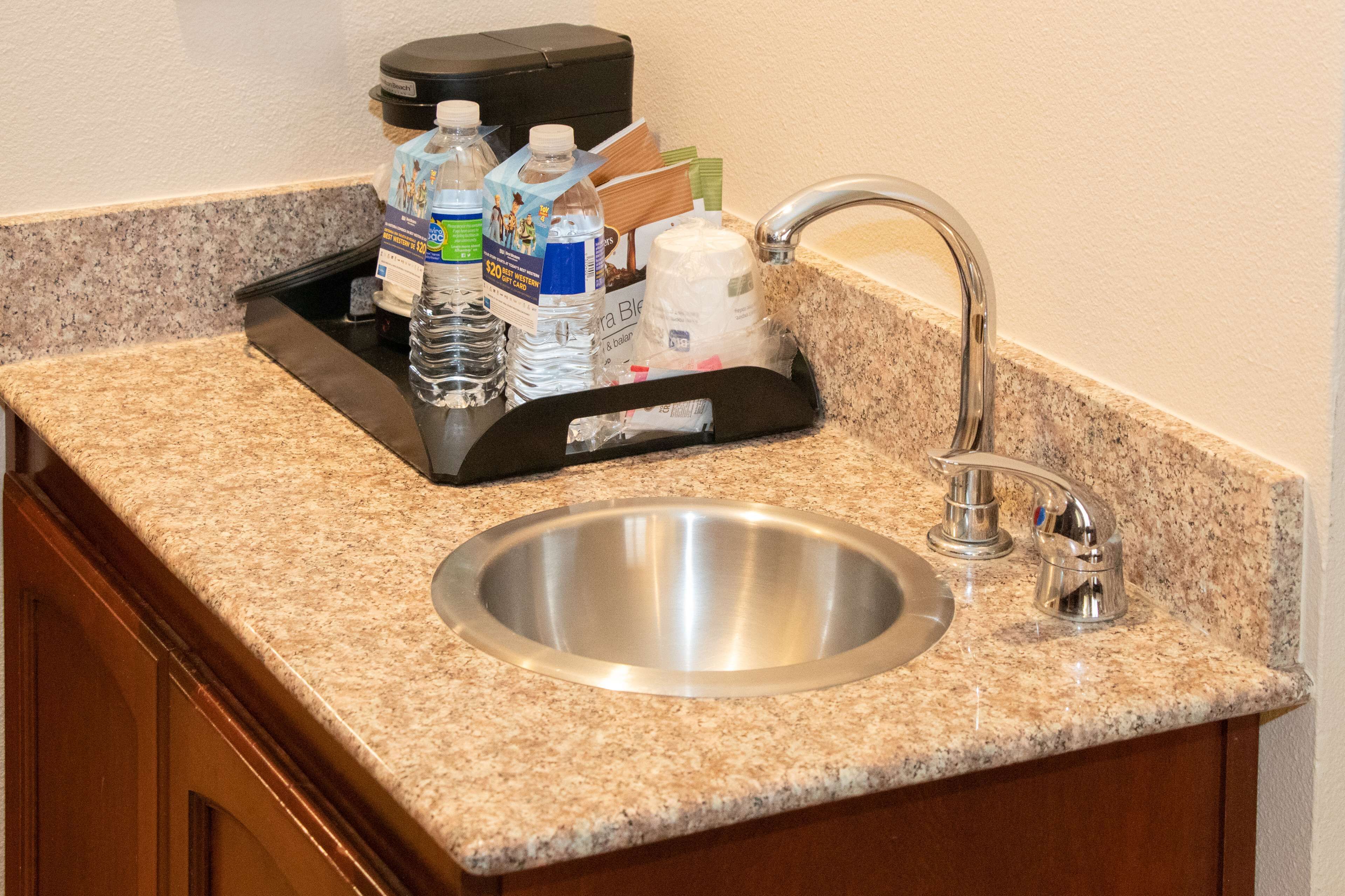 A kitchen counter with a stainless steel sink, a coffee maker, and a water dispenser.