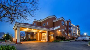 A multi-story hotel with a covered entrance, large windows, and a parking area. - Best Western I-5 Inn & Suites (Lodi)