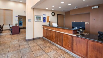 A reception area with a wooden reception desk, a clock, and a security camera on the ceiling.