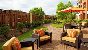 An outdoor patio area with wicker furniture, a brick floor, and a wooden fence. - Courtyard by Marriott Akron Stow (Stow)