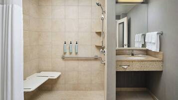A bathroom with beige tiles, a shower, a sink with a mirror, and a towel rack.