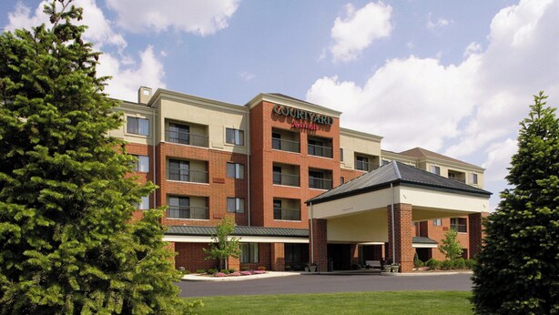 A Courtyard by Marriott hotel with a brick facade, multiple floors, and a covered parking area. - Courtyard by Marriott Akron Stow (Stow)