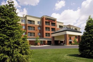 A Courtyard by Marriott hotel with a brick facade, multiple floors, and a covered parking area.