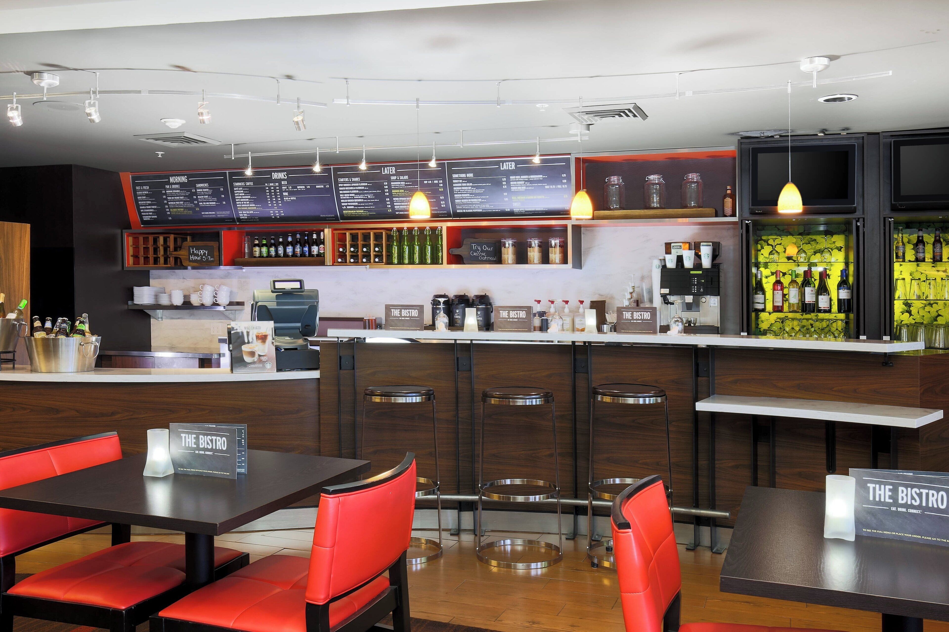 A restaurant with a bar area, multiple seating options including bar stools and tables, and a menu board above the bar.