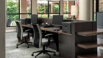 Un espace de bureau moderne, doté de cloisons, de chaises ergonomiques et offrant une vue sur la verdure grâce à de grandes fenêtres.