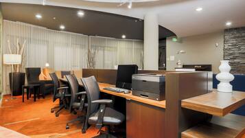 Zona de recepción de un hotel con un mostrador, sillas, una computadora e impresora.