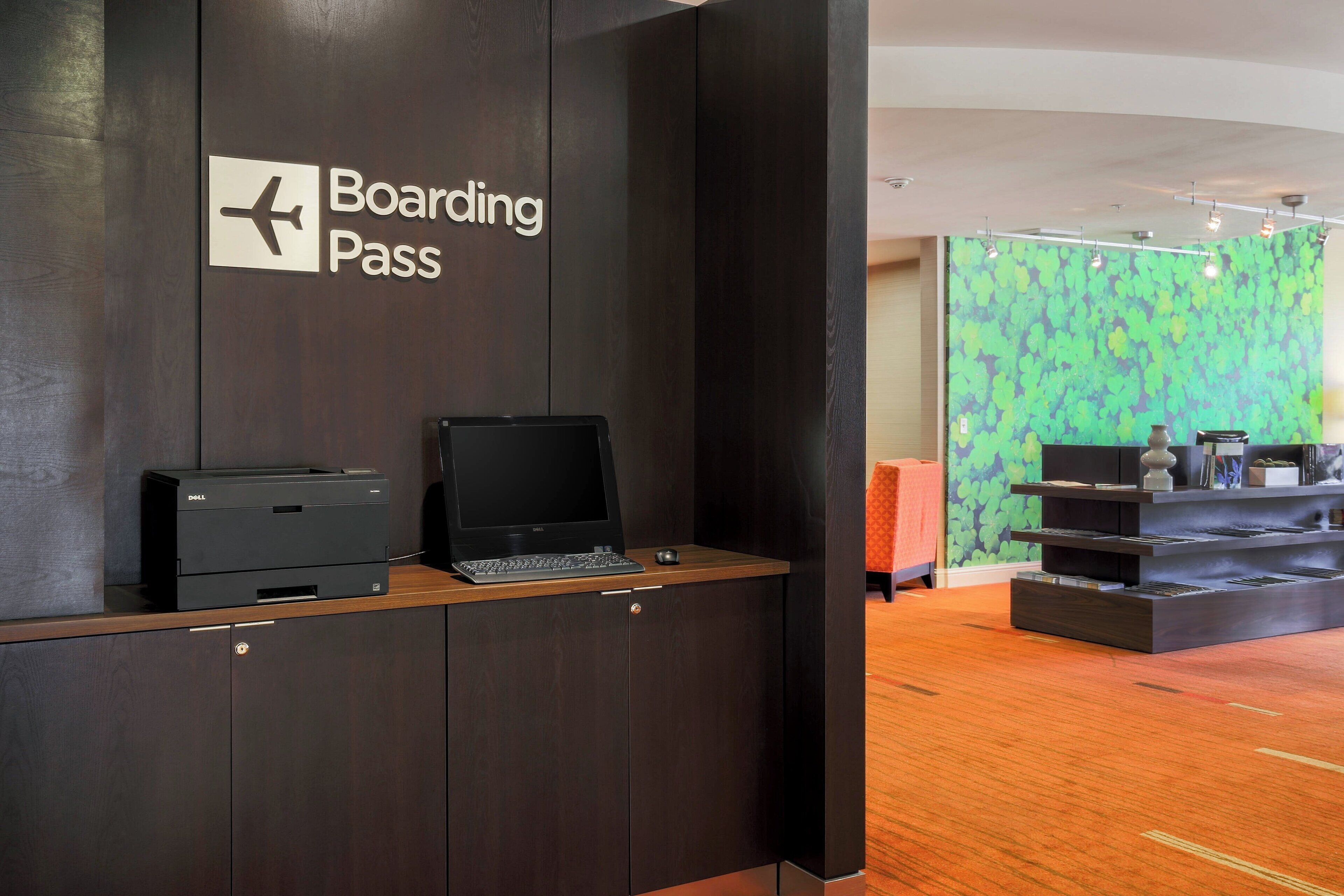 Un mostrador de recepción con un cartel que dice "Boarding Pass" y una impresora Dell.