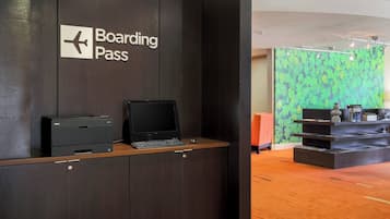 Un mostrador de recepción con un cartel que dice "Boarding Pass" y una impresora Dell.