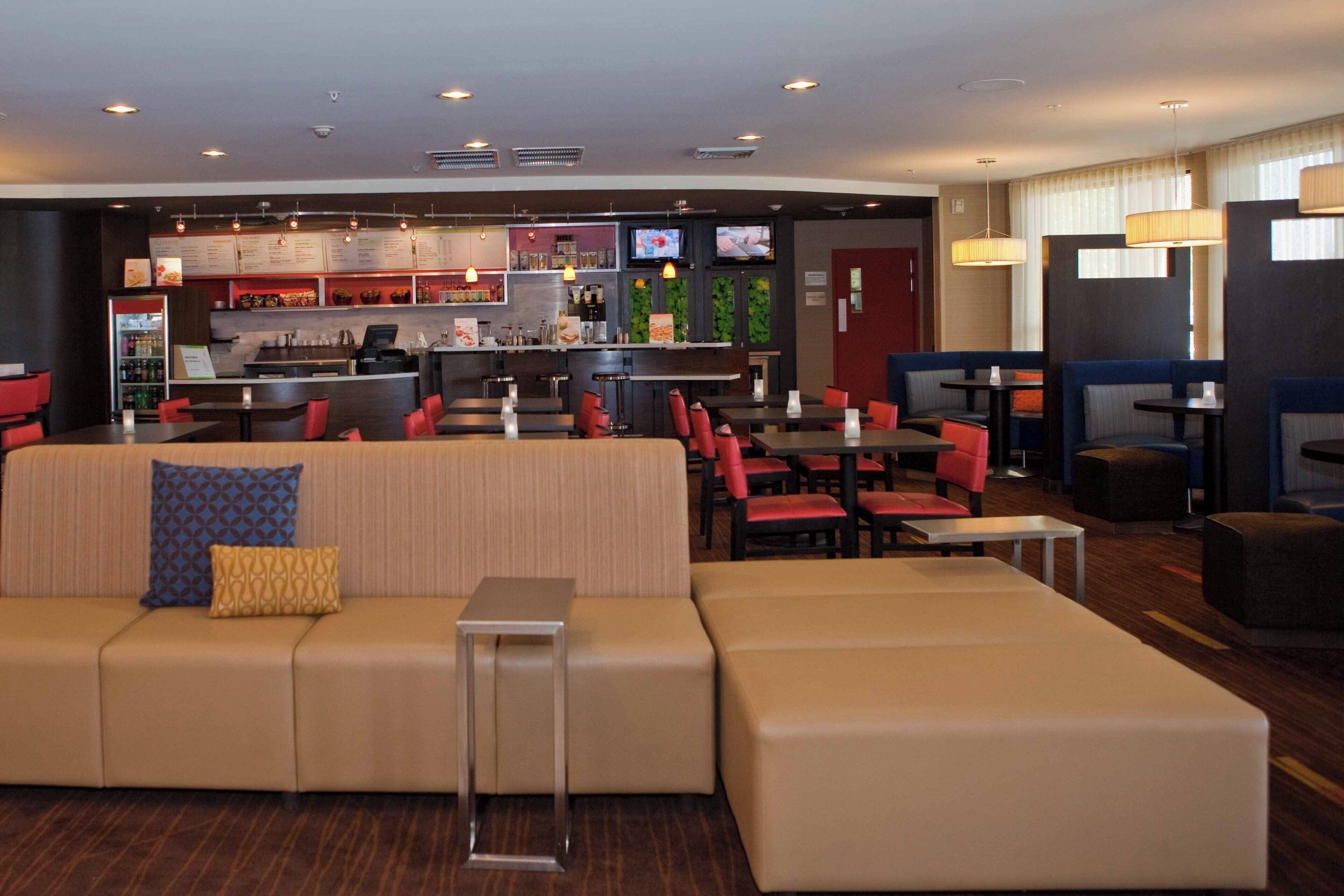 Un moderno vestíbulo de hotel con una zona de bar, áreas de descanso y una recepción.