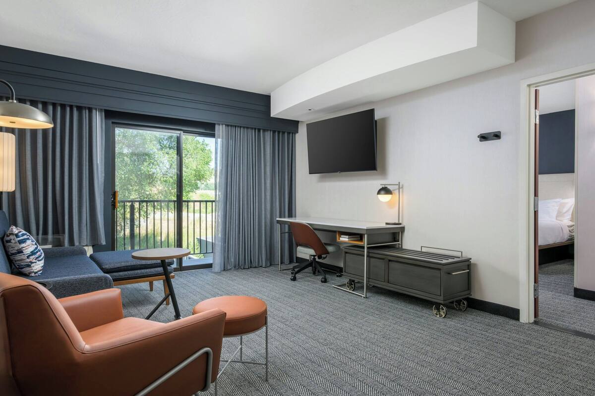A hotel room with a sofa, a desk, a TV, and a bed.