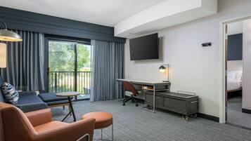 A hotel room with a sofa, a desk, a TV, and a bed.