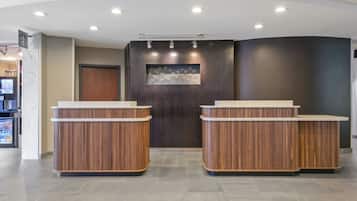 A reception area with two wooden reception desks, a dark wall with a decorative panel, and a door.