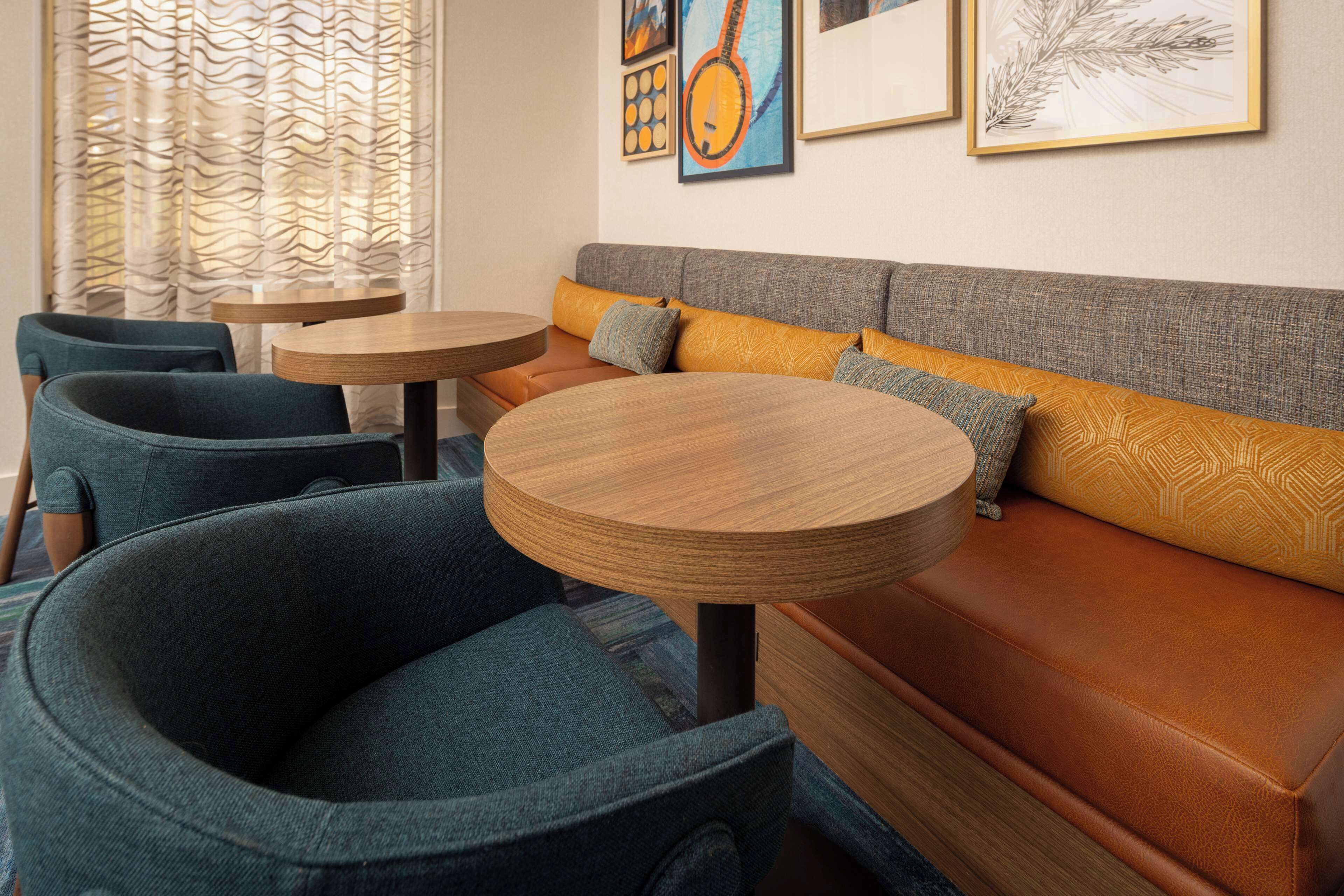 A cozy seating area with a sofa and two round tables, surrounded by chairs.