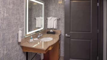 A bathroom with a granite countertop, two sinks, a large mirror, and a towel rack.