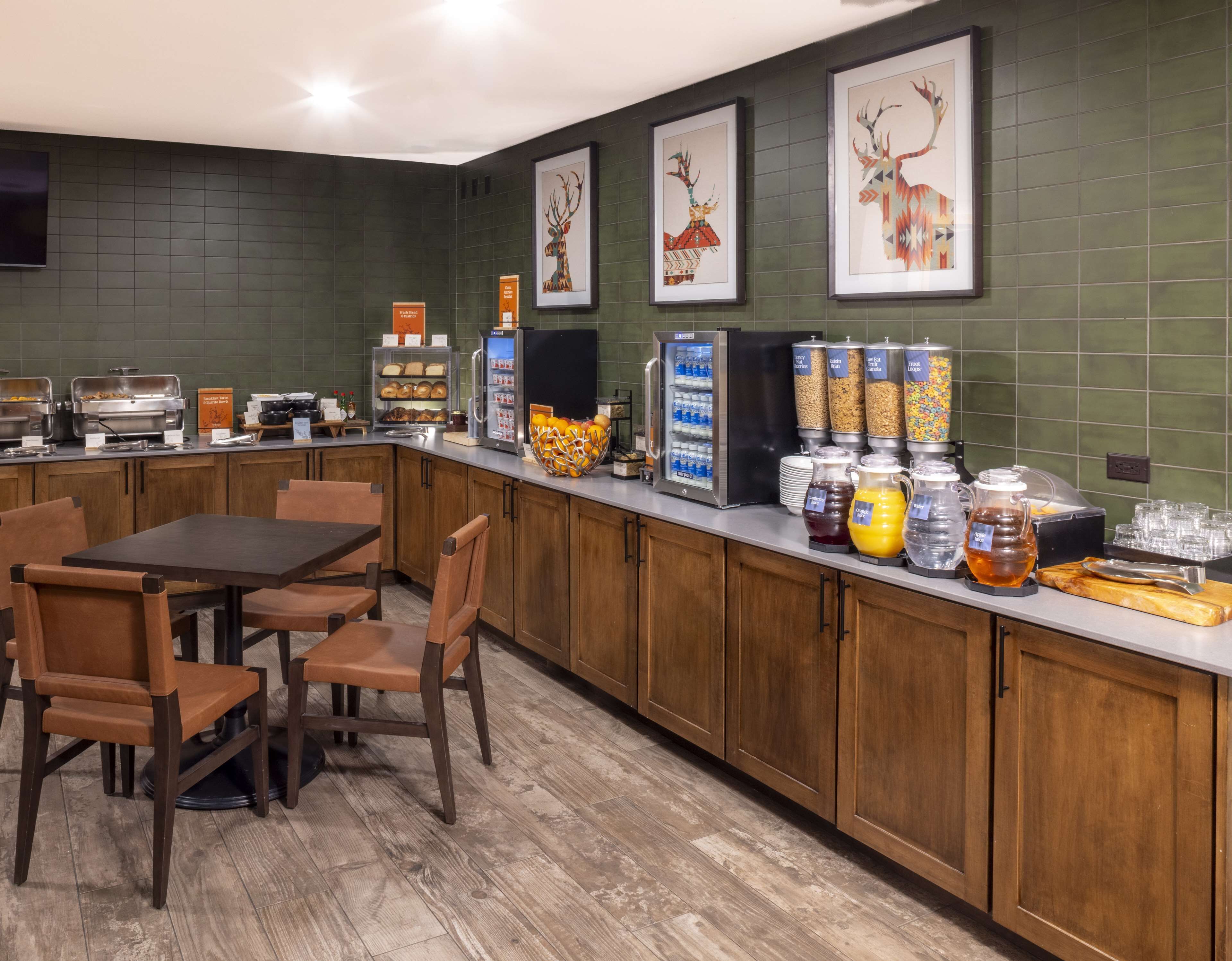 A breakfast bar with a variety of food and drink options, including a fruit bowl, cereal, and a coffee machine.