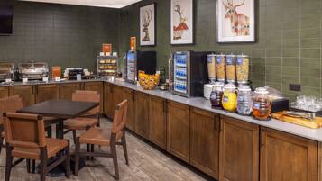 A breakfast bar with a variety of food and drink options, including a fruit bowl, cereal, and a coffee machine.