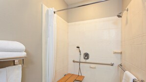 A shower area with a wooden shelf, grab bars, and a towel rack. - Holiday Inn Express Hotel & Suites Wharton by IHG (Wharton)