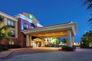 Edificio de Holiday Inn Express & Suites con un acceso cubierto y cielo despejado.