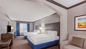 A hotel room with a large bed, a sofa, a desk, and a TV. - Holiday Inn Express Hotel & Suites Wharton by IHG (Wharton)