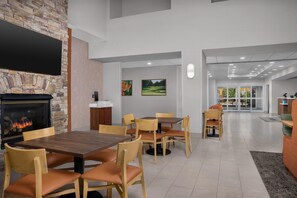 A restaurant with a stone fireplace, wooden tables and chairs, and a flat-screen TV mounted on the wall.