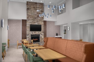 A modern interior with a stone fireplace, wooden tables and chairs, and a large orange sofa.