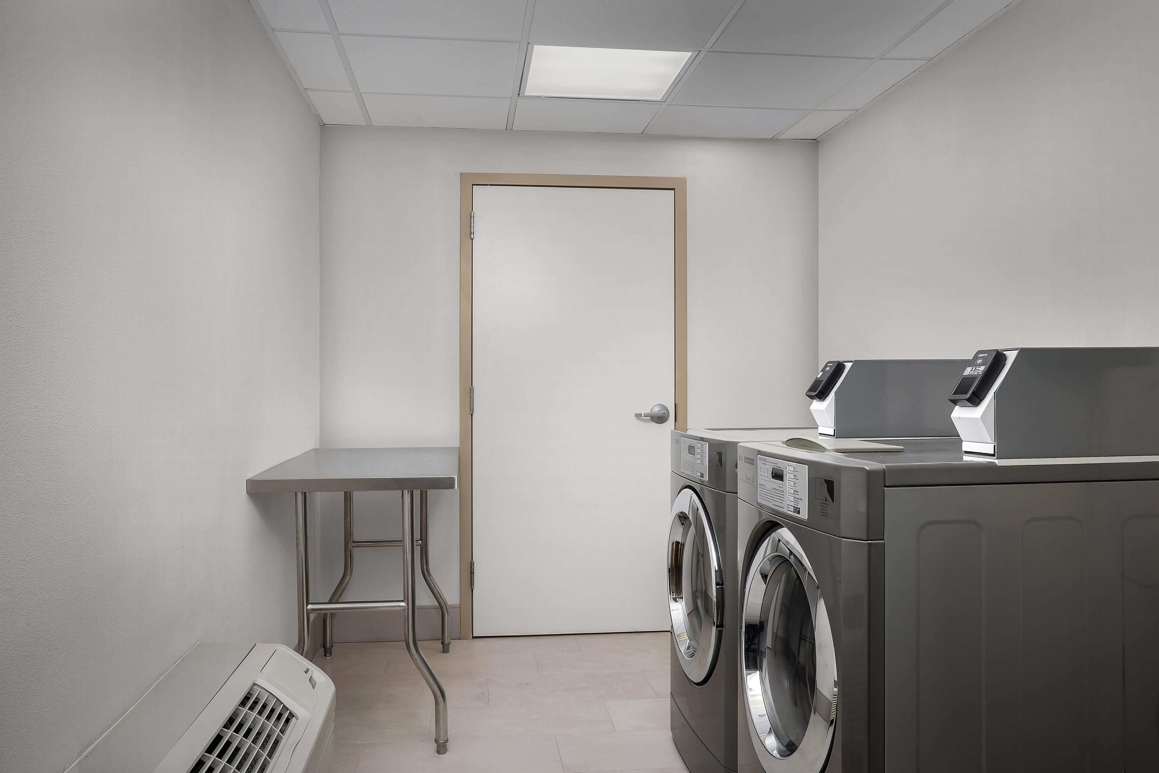 A laundry room with a washing machine, dryer, and a small table.