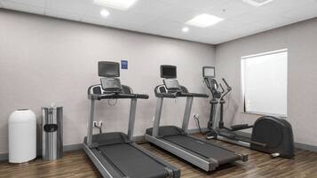Ein Fitnessraum mit drei Laufbändern, einem Ergometer und zwei Mülleimern.